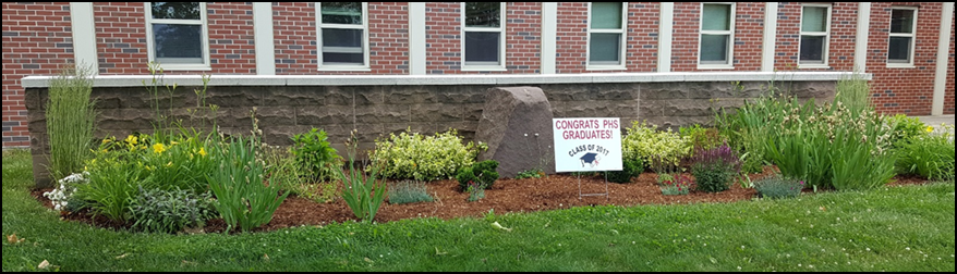 Memorial garden in front of school. Small sign with graduation announcement is placed in the garden. 
