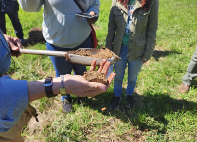 hand outstretched with handful of soil with people observing